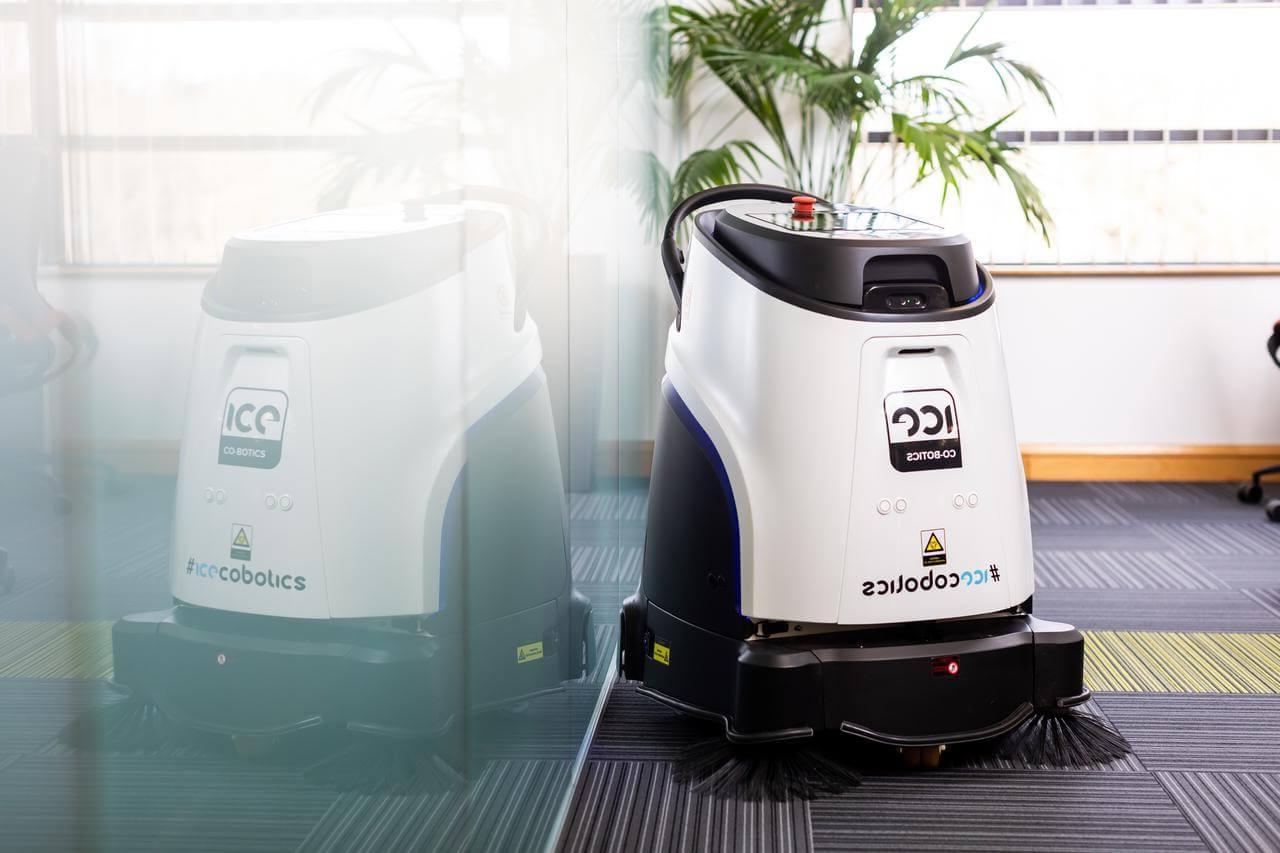 Mitie cleaning robot in an office, reflected in a glass partition